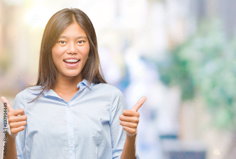 Young asian business woman over isolated background success sign doing positive gesture with hand, thumbs up smiling and happy. Looking at the camera with cheerful expression, winner gesture.