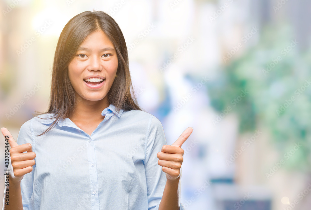 Fototapeta premium Young asian business woman over isolated background success sign doing positive gesture with hand, thumbs up smiling and happy. Looking at the camera with cheerful expression, winner gesture.