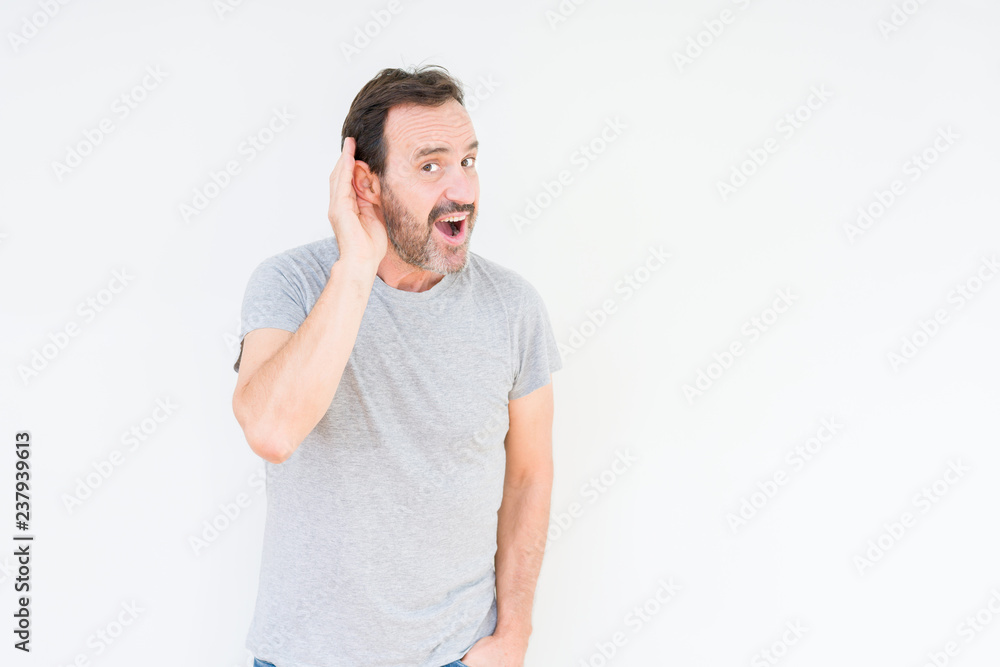 Handsome senior man over isolated background smiling with hand over ear listening an hearing to rumor or gossip. Deafness concept. Handsome senior man over isolated background smiling with hand over ear listening an hearing to rumor or gossip. Deafness concept.