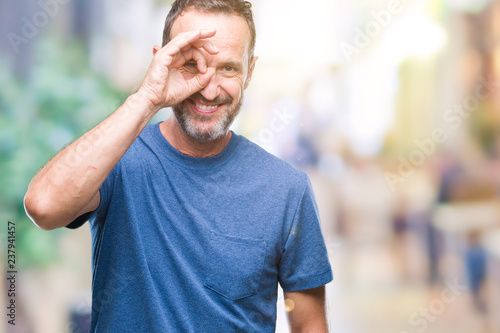 Middle age hoary senior man over isolated background doing ok gesture with hand smiling, eye looking through fingers with happy face.