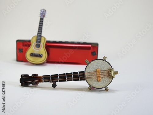 Obraz na płótnie A miniature banjo and a miniature acoustic guitar propped up on a red 10-hole diatonic harmonica