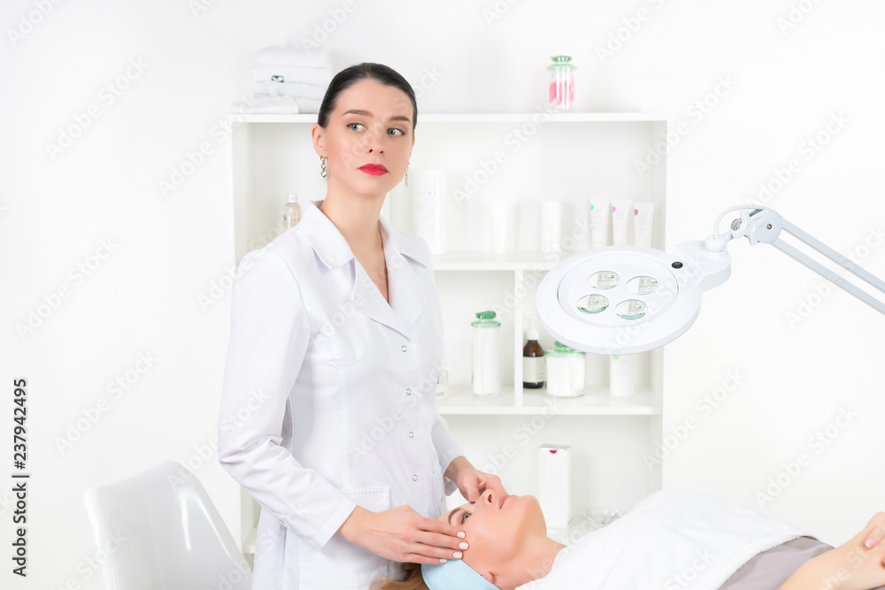 Female beautician doctor with patient in wellness center. Professional cosmetologist make procedure to beautiful girl in cosmetology cabinet or beauty parlor. Female beautician doctor with patient in wellness center. Professional cosmetologist make procedure to beautiful girl in cosmetology cabinet or beauty parlor.