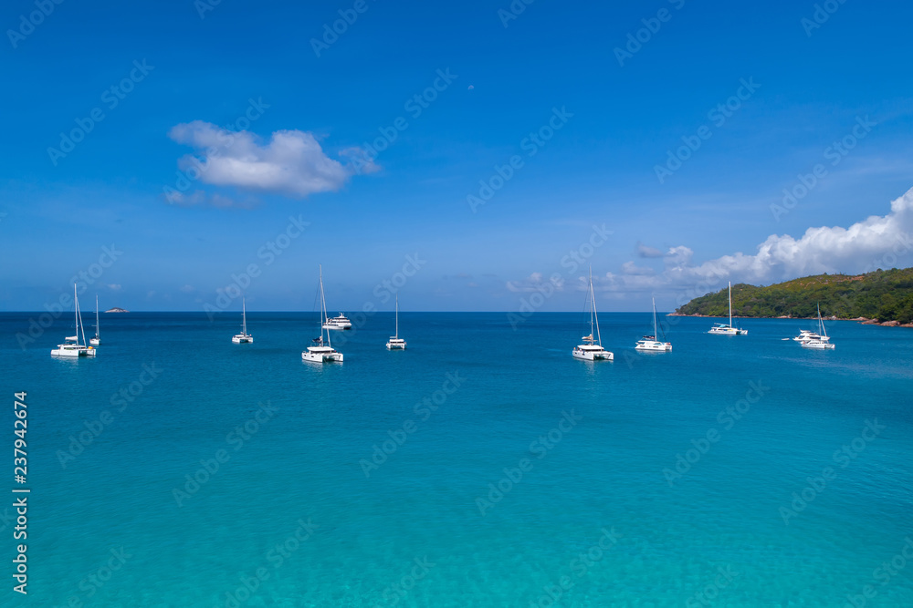 Spectacular aerial view of some yachts and small boats floating on a clear and turquoise sea, Seychelles in the Indian