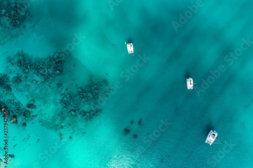 Spectacular aerial view of some yachts and small boats floating on a clear and turquoise sea, Seychelles in the Indian Ocean.Top view from drone