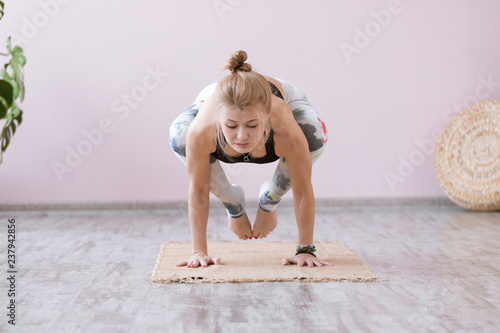 Yoga woman training on exercise mat and doing balance yoga poses on white background. Astavakrasana or symmetrical arm balance pose. photo