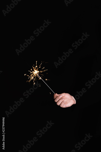 Man's hand holding burning sparkler on a black background
