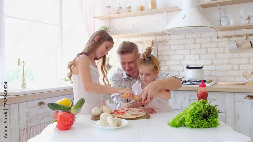 Father and daughters having a fun in the kitchen and making pizza Father and daughters having a fun in the kitchen and making pizza