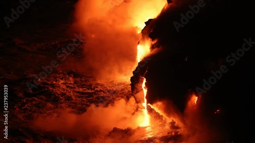 Lava flowing in the ocean and huge rock falls breaking off from volcanic lava eruption on Big Island Hawaii. Lava meets the Ocean in dramatic spectacle. Kilauea volcano. Night shot slow motion.