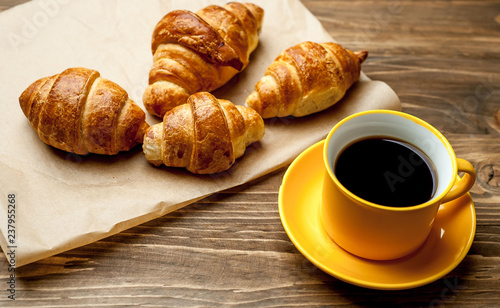 mug of coffee, croissants on wooden background