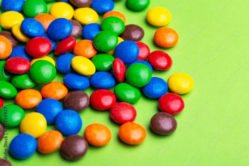 Glazed colored chocolate candies are gathered on bright green background Glazed colored chocolate candies are gathered on bright green background
