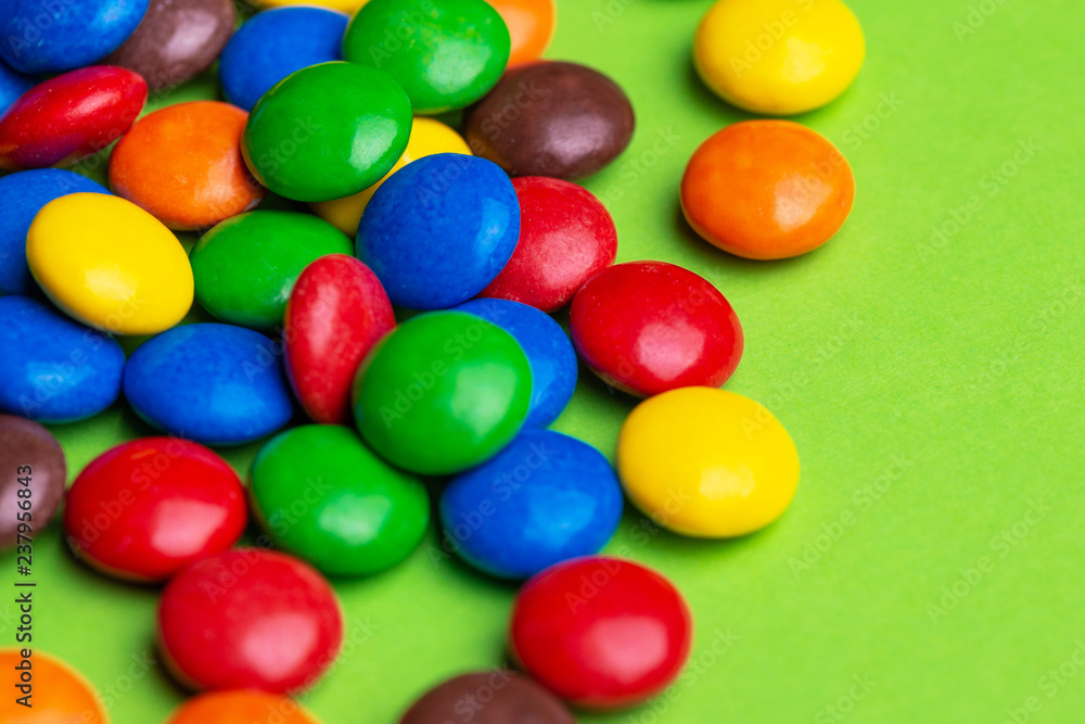 Glazed colored chocolate candies are gathered on bright green background Glazed colored chocolate candies are gathered on bright green background