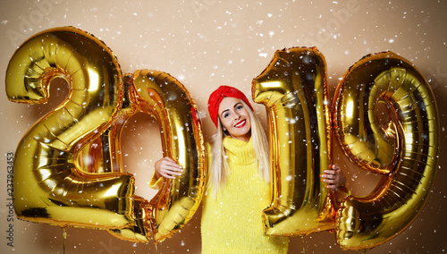 Woman celebrating New Year xmas party happy laughing in yellow sweater blouse with 2019 gold balloons  © Dmitry Lobanov