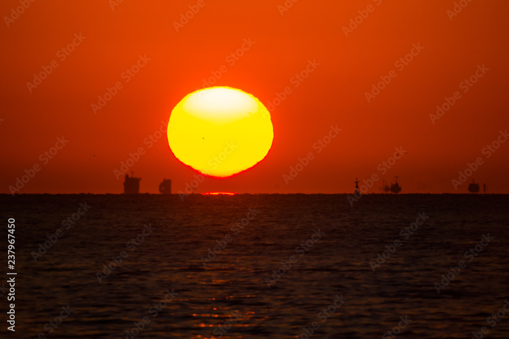 水平線の日の出と沖の船影