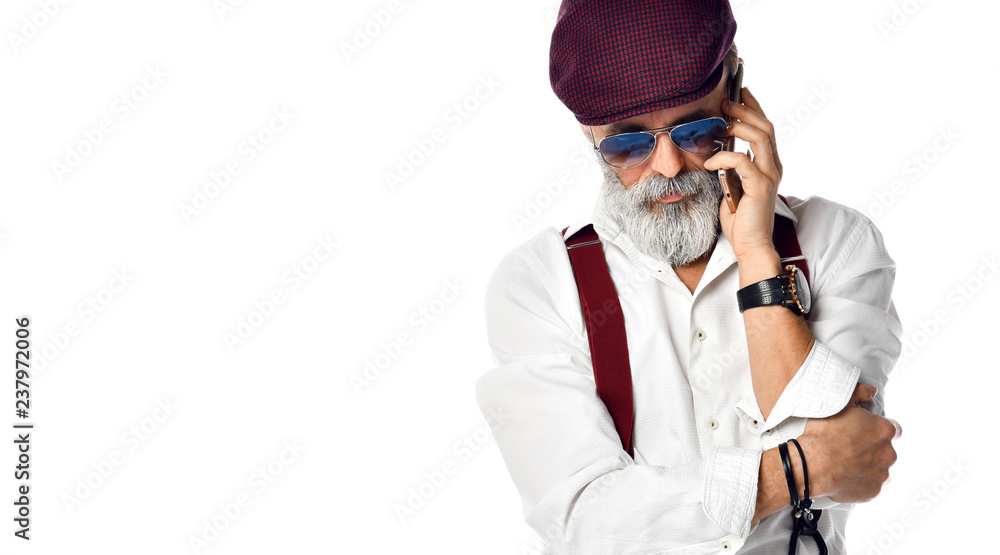 Old brutal senior millionaire man in cap talking on the mobile phone in aviator sunglasses  