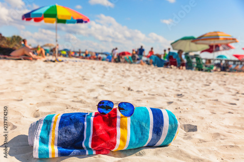 Beach towel and fashion sunglasses on Florida beach background -summer vacation travel concept copy space. Crowded popular USA destination for american holidays.