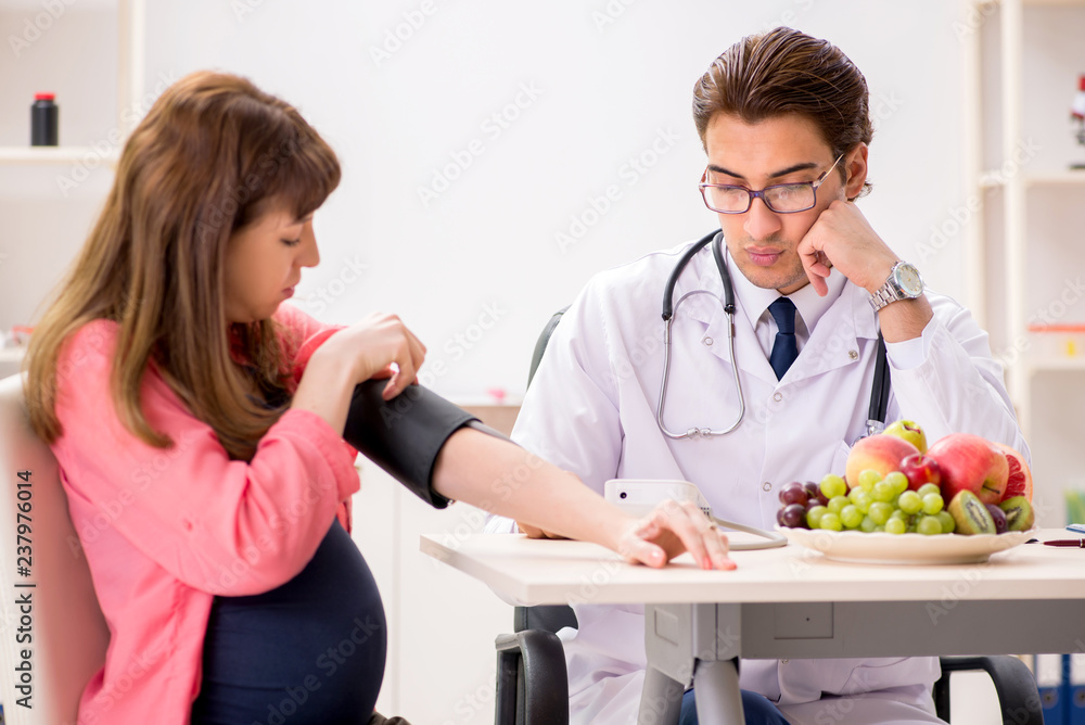 Pregnant woman visiting doctor discussing healthy diet Pregnant woman visiting doctor discussing healthy diet