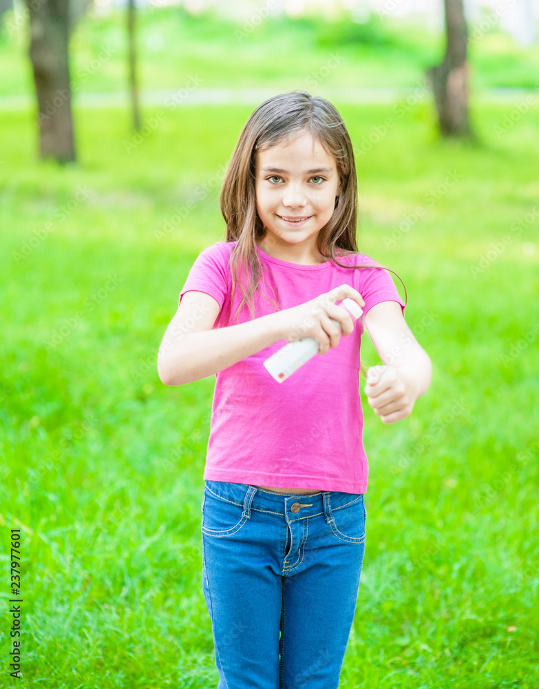 Happy little girl spraying insect repellents on skin