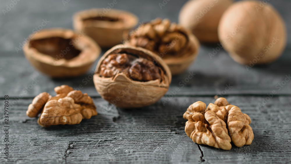 Ripe walnuts split and scattered on a dark wooden table. Ripe walnuts split and scattered on a dark wooden table.