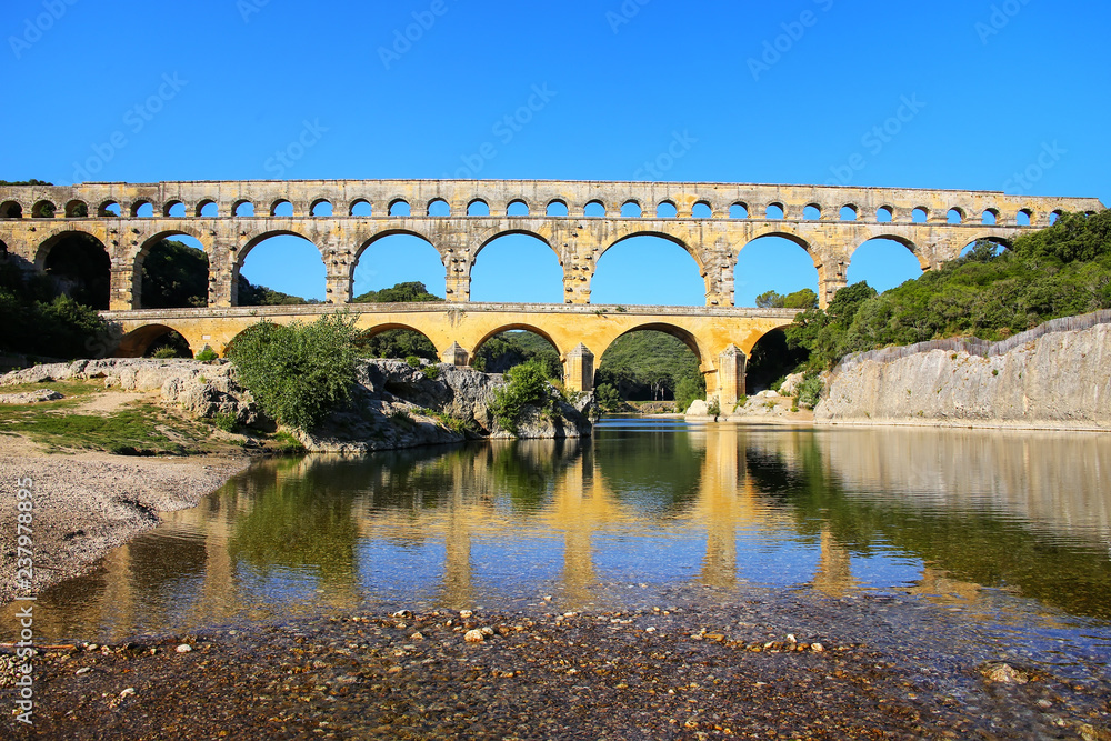 Fototapeta premium Aqueduct Pont du Gard reflected in Gardon River, southern France