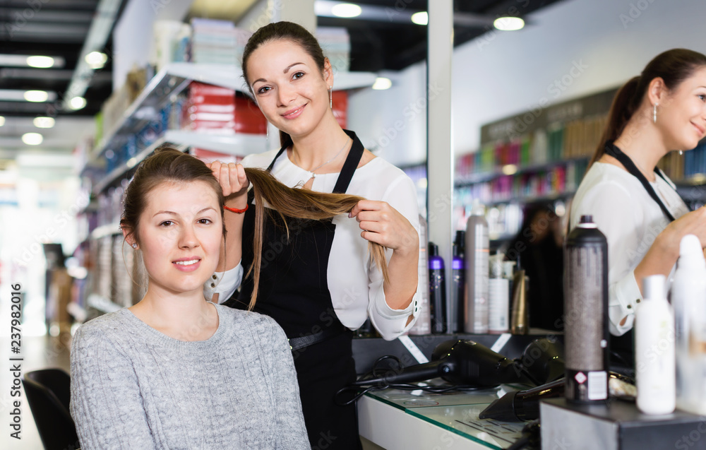 Young female hairdresser with male visitor in beauty salon