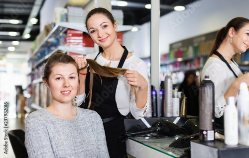 Young female hairdresser with male visitor in beauty salon
