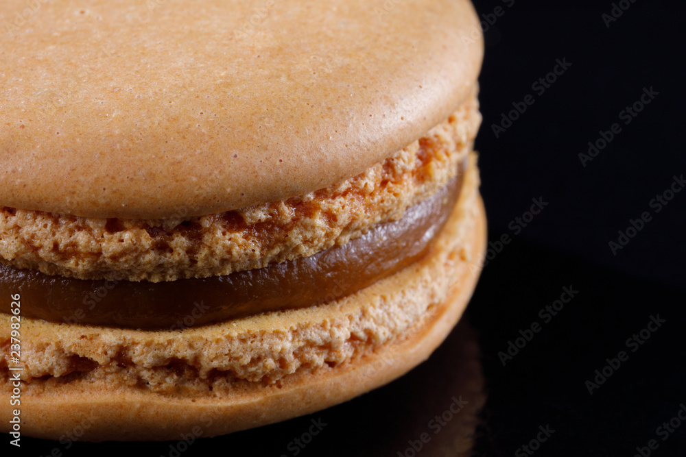 Bright juicy delicious macarons of almond color on a black background. Bright juicy delicious macarons of almond color on a black background.