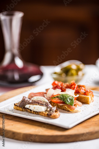 Tasty italian appetizer bruschettes with tomatoes anchovies prosciutto and mozarella