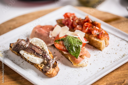 Tasty italian appetizer bruschettes with tomatoes anchovies prosciutto and mozarella