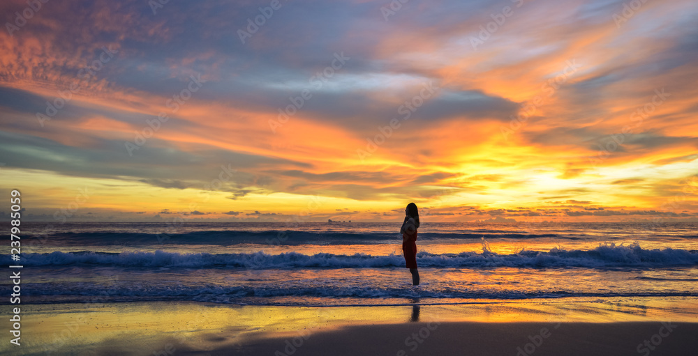 silhouette of single Asian girl enjoying herself during sunset, photo taken on Lanta island beach, Krabi, Thailand.
