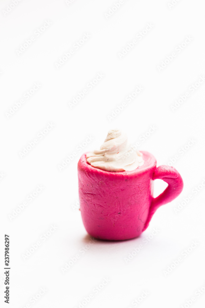 Obraz premium Miniature play dough coffee or latte cup with cream topping, piece of cake on pink plate, white isolated background, artificial food concept, kids craft sculpture, mini art, copy space, coffee shop