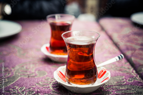 Turkish or Azerbaijani tea in pear shape glasses with saucers on ethnic national table cloth, traditional eastern hot black tea for Ramadan or Novruz, copy space