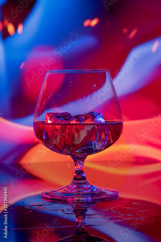 Glass of cognac with ice on a bright background
