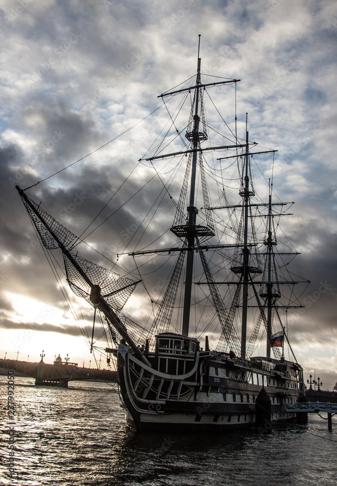 Old sailing ship at the city pier on a background of gray sky Old sailing ship at the city pier on a background of gray sky