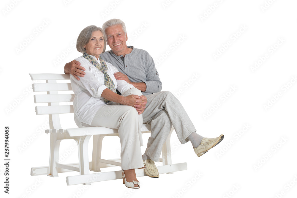 Portrait of senior couple sitting on bench on white background Portrait of senior couple sitting on bench on white background