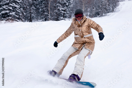 Professional woman snowboarder in bright sportswear and outfit skiing downhill in snowy sunny high mountains. Blur, soft focus, object in motion