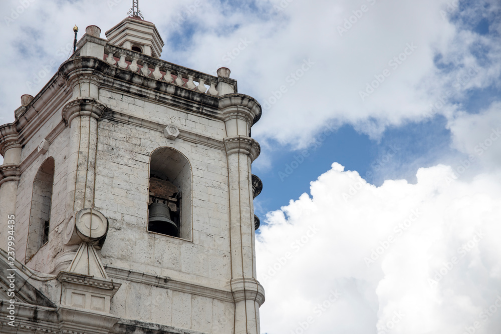 Old catholic church. White stone bell tower on blue sky background. Basilica de Santo Nino in Cebu,