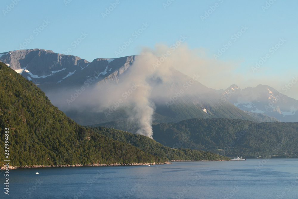 Fire and mountains on fjord coast. Sykkylven Ferjekai, Norway