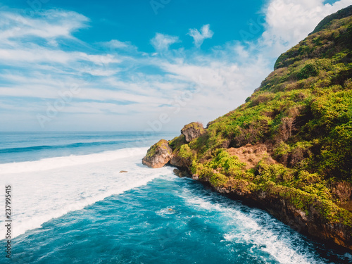 Aerial view of cliff and blue ocean with waves in Bali, Indonesia.