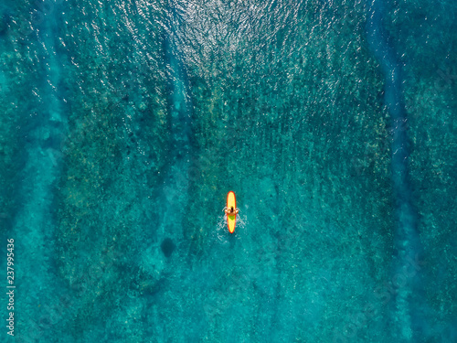 Aerial view with surfer woman on surfboard in blue ocean. Top view
