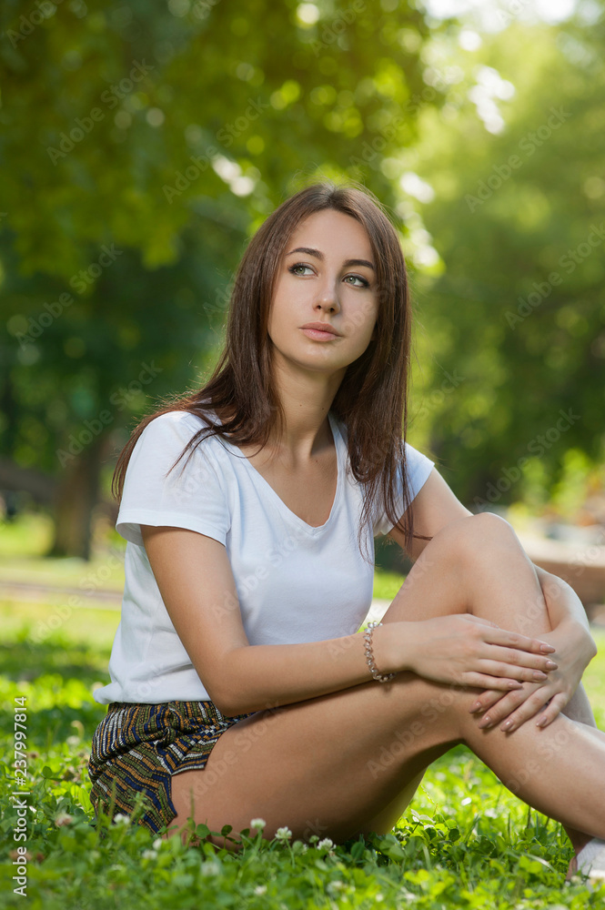 Naklejka premium Charming Student Girl Sitting on Green Grass
