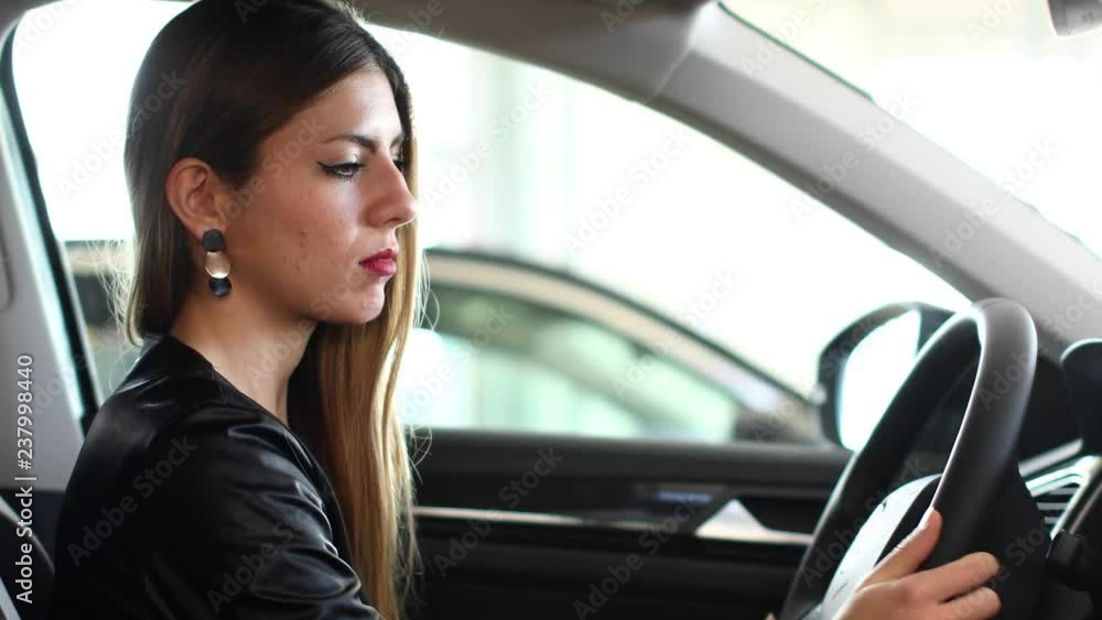 Young woman smiling in her new car in a showroom Young woman smiling in her new car in a showroom