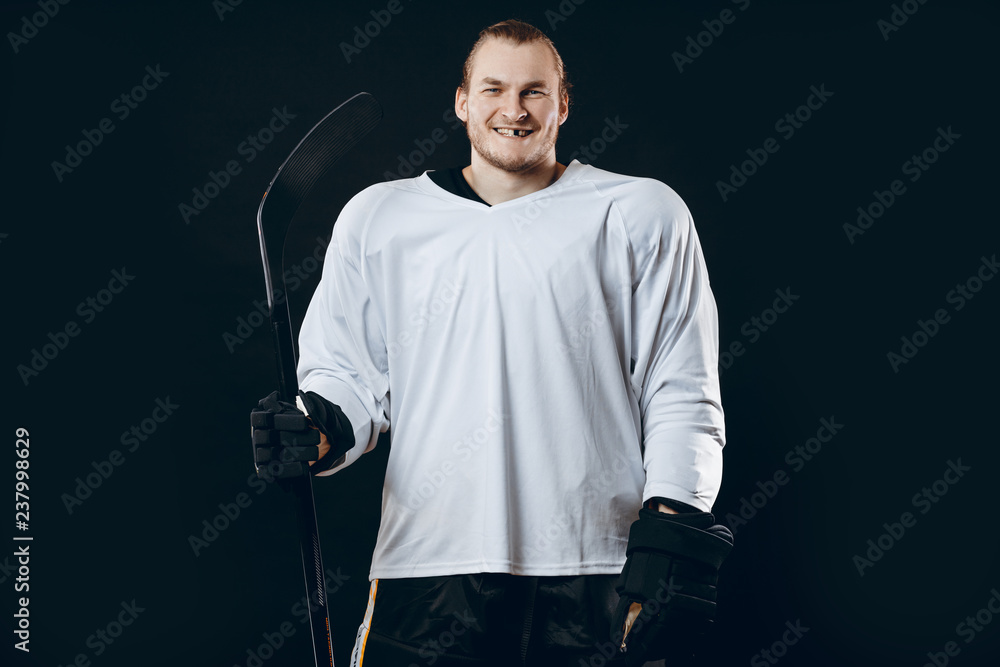 Naklejka premium Portrait of cheerful proud caucasian hockey player smiling with teeth, looking in camera with happy and relaxed face expression, posing after victory in hockey match with stick, isolated on white