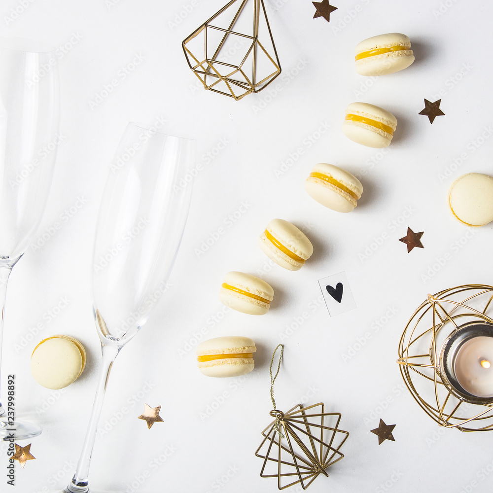 Yellow lemon macaroons on a white background next to champagne glasses. Festive gourmet Christmas aperitif. Top view, flat lay Yellow lemon macaroons on a white background next to champagne glasses. Festive gourmet Christmas aperitif. Top view, flat lay