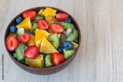 Healthy fresh fruit salad in bowl on light background