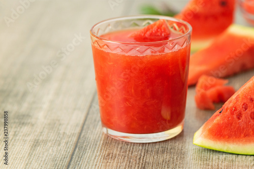 Glass of Watermelon smoothie with fresh watermelon slices on gray wooden background
