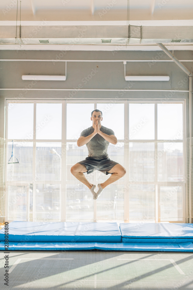 active sportsman performs lotus posture during jumping on the trampoline. full length photo. crazy position of yoga active sportsman performs lotus posture during jumping on the trampoline. full length photo. crazy position of yoga