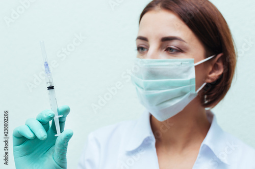 Young nurse in glasses prepares syringe