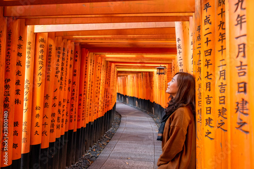 A beautiful asian woman with orange torii gates path in background