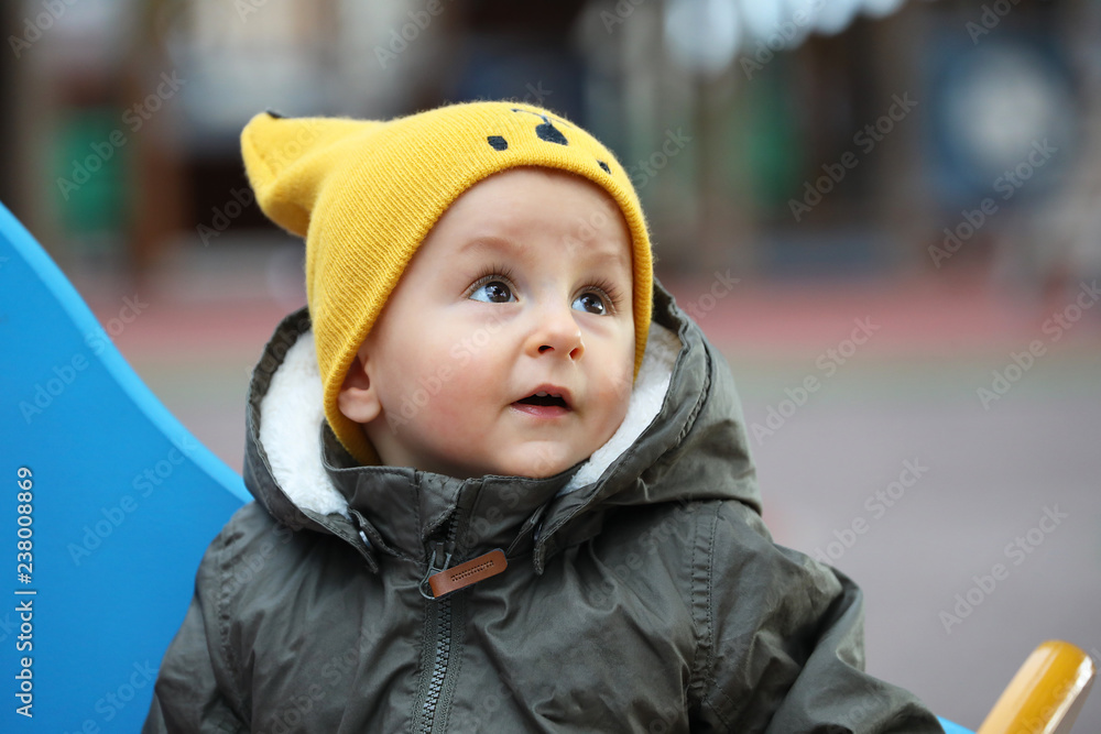 Baby With A Funny Yellow Hat And A Winter Jacket Baby With A Funny Yellow Hat And A Winter Jacket