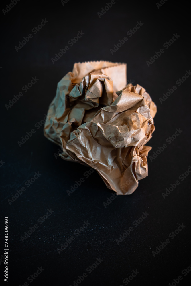 The brown crumpled paper balls on the dark background. The brown crumpled paper balls on the dark background.